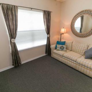 A cozy living room with a sofa, mirror, and window with curtains.