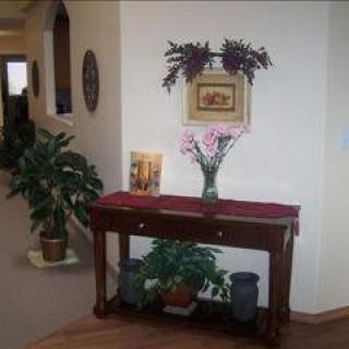A hallway with a decorative console table adorned with a vase of flowers, plants, and framed artwork.