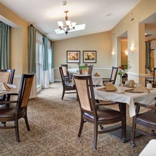 A well-appointed dining room with neatly arranged tables and chairs, featuring elegant decor and lighting.