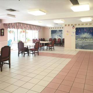 A spacious dining area with tables and chairs arranged neatly on a tiled floor, featuring a decorative mural on the wall.