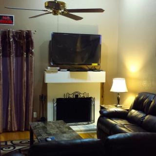 A cozy living room with a sofa, lamp, fireplace, and television.