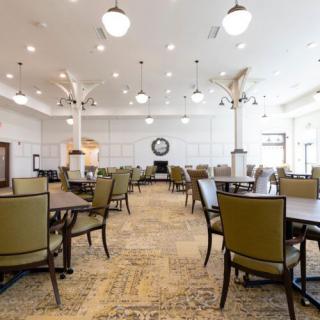 An empty dining room with neatly arranged tables and chairs, featuring stylish lighting and decor.