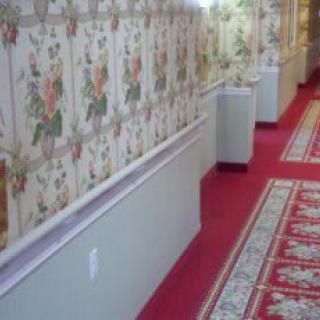 A traditionally styled hallway with floral wallpaper and a red carpet.