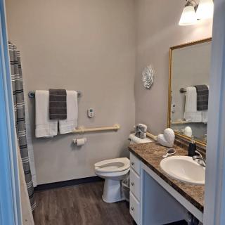 A well-lit bathroom with a toilet, sink, and towels neatly arranged.