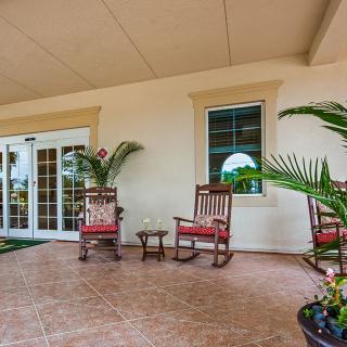 A cozy porch with rocking chairs and potted plants, featuring glass doors and windows.