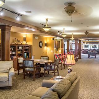 A cozy and well-lit living room area with comfortable seating and a bookshelf.
