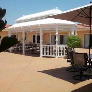 A serene outdoor space featuring a white gazebo and comfortable seating under umbrellas.