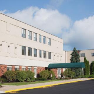 An exterior view of a large institutional building with a green awning.