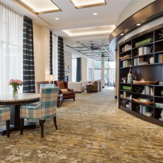 A modern library interior with bookshelves, comfortable seating, and abundant natural light.