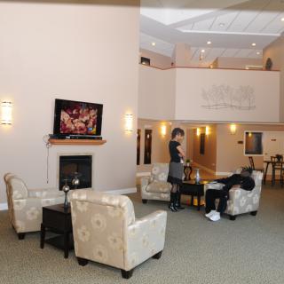 A spacious lobby with comfortable seating, a fireplace, and a television.