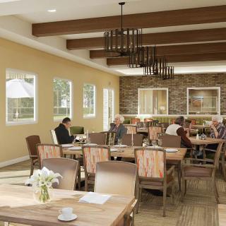 A cozy dining room with people seated at tables, featuring wooden furniture and elegant chandeliers.