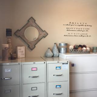 A cozy office space featuring stylish filing cabinets, a decorative mirror, and thoughtful wall art.