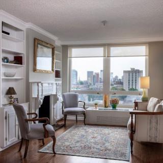 A cozy living room with elegant furniture and a large window overlooking the city skyline.