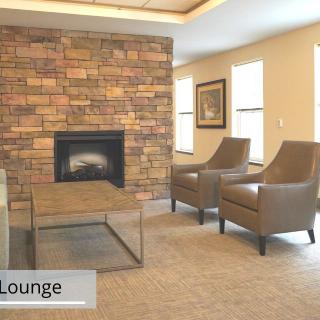 A cozy lounge area featuring a brick fireplace, two chairs, and a glass coffee table.