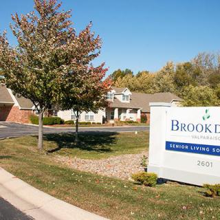 Entrance to a residential facility with a sign and fall foliage.