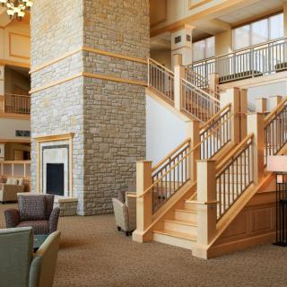 A modern lobby with a stone fireplace and wooden staircase.
