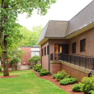 A tranquil scene featuring a brick building surrounded by lush greenery.