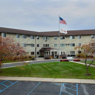 A multi-story building with an American flag in front, surrounded by a landscaped area and parking lot.