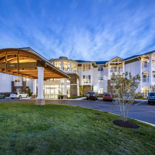 A modern hotel building with a well-lit entrance and landscaped surroundings during the evening.