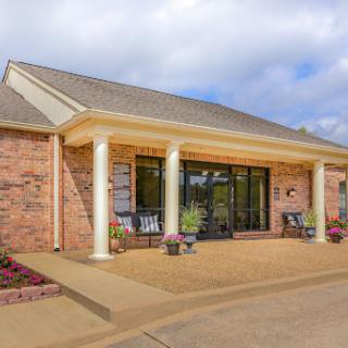A charming residential house featuring a brick exterior and welcoming front porch.