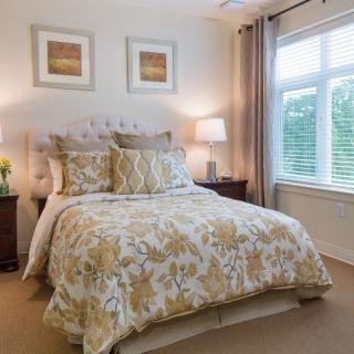 A cozy and well-decorated bedroom featuring a comfortable bed with floral bedding, bedside tables with lamps, and artwork on the walls.