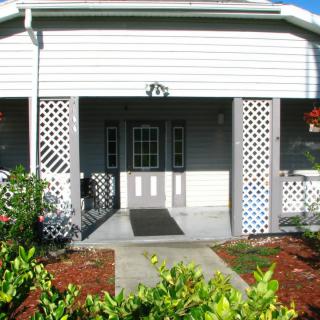 Front entrance of a house with a porch and surrounding greenery.