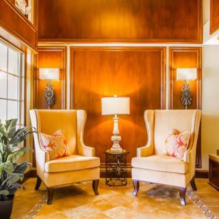 A cozy living room setting with two armchairs and a lamp against wood paneled walls.
