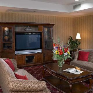 A cozy living room with classic furniture, featuring a large television and a floral centerpiece on the coffee table.