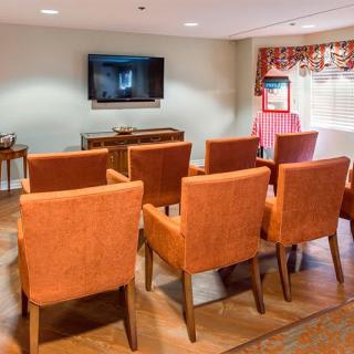 A small meeting room with rows of orange chairs facing a television.