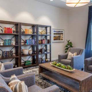 A cozy living room with modern furnishings, featuring a large bookshelf and comfortable seating.
