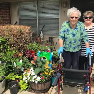 Two women enjoying a day of gardening with various plants and flowers.