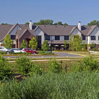 A suburban residential area with houses, greenery, and a parking lot with cars.