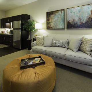 A modern living room with a comfortable sofa, stylish artwork, and a cozy ottoman.