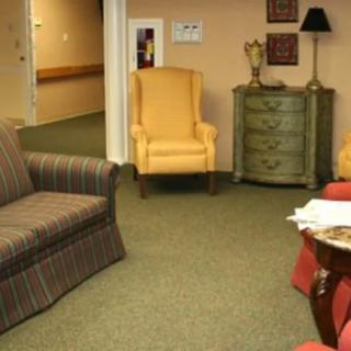 A cozy living room with a sofa, armchairs, and a side table on a green carpet.