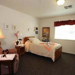 A cozy bedroom with a single bed, adorned with simple decor and illuminated by natural light from a window.