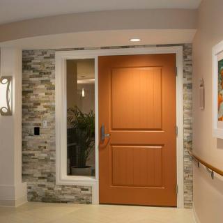 A modern interior entrance featuring a wooden door, stone wall accents, and a light fixture.