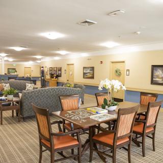 A spacious interior with a dining area featuring a wooden table and chairs, surrounded by comfortable seating and bright lighting.
