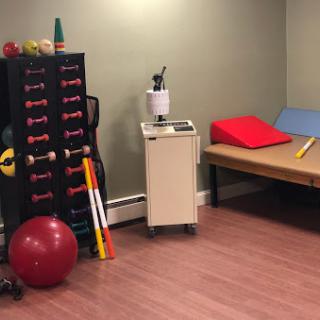 A well-equipped therapy room featuring various exercise tools and a bench for rehabilitation.