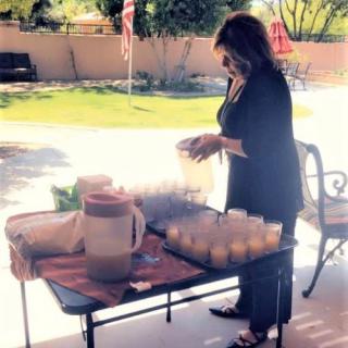 A person setting up a table with beverages and cups outdoors in a garden.