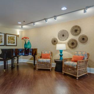 A cozy living room with rattan chairs and colorful decor, featuring a stylish arrangement of wall art and a vibrant table lamp.