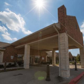 A brick building entrance under a sunny sky with clouds.