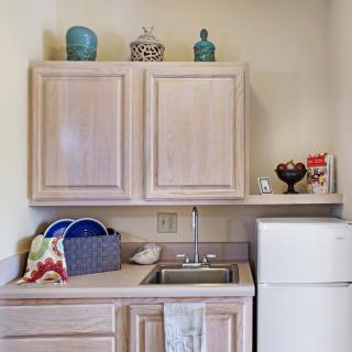 A compact kitchen area with wooden cabinets, a sink, and a small refrigerator.