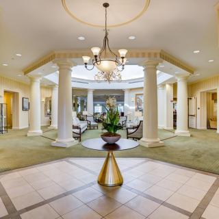 Luxurious lobby with chandelier, columns, and seating area.