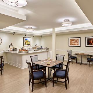 A modern dining area with tables and chairs, featuring minimalist decor and artwork on the walls.