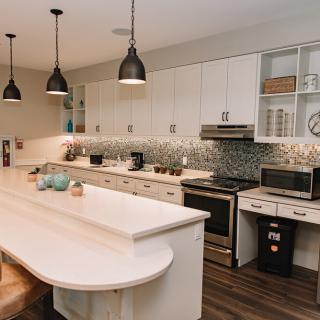 A modern kitchen with white cabinets, a central island, and stylish pendant lights.