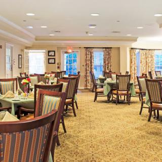 An elegant dining area with neatly arranged tables and chairs, featuring warm lighting and tasteful decor.