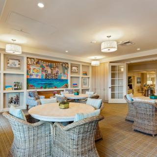 A cozy and bright lounge area with wicker furniture and decorative artwork on the walls.