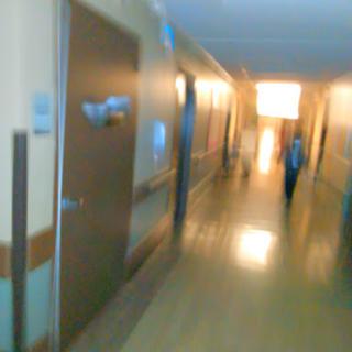 A blurred view of a hospital hallway, illuminated by soft lighting.