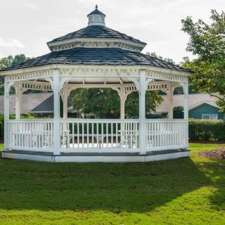 A charming white gazebo in a lush garden setting.