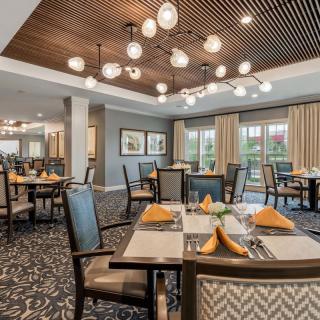 A spacious and elegantly decorated dining room with modern lighting and neatly arranged tables.